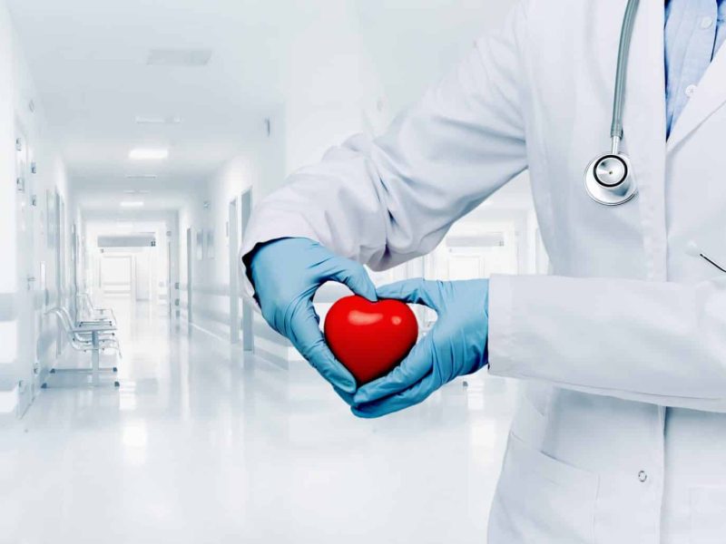 female doctor in white uniform with red heart shape with hands