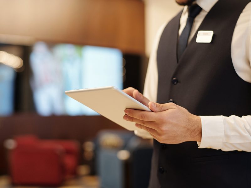 Close up of young male receptionist using tablet during work