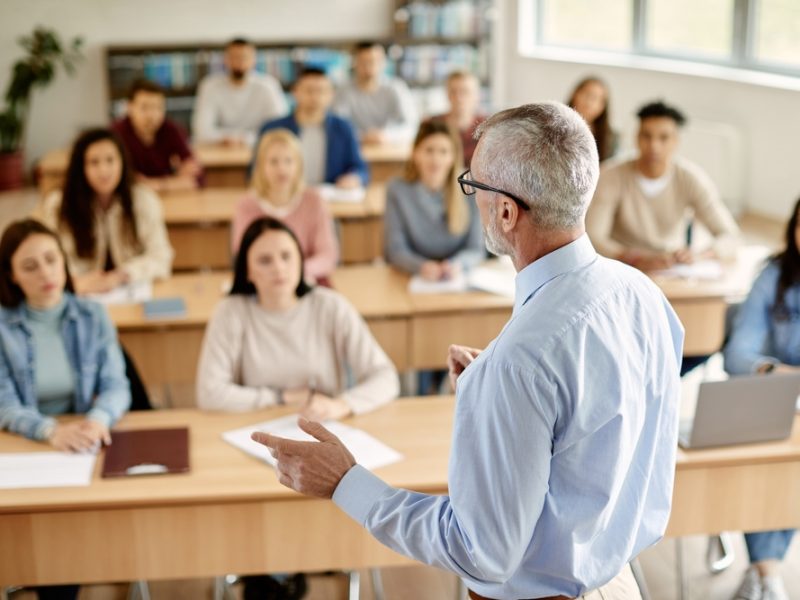 Back,View,Of,Mature,Professor,Giving,Lecture,To,Large,Group