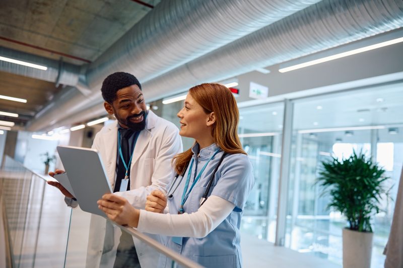 Happy,African,American,Doctor,Using,Cell,Phone,While,Talking,To