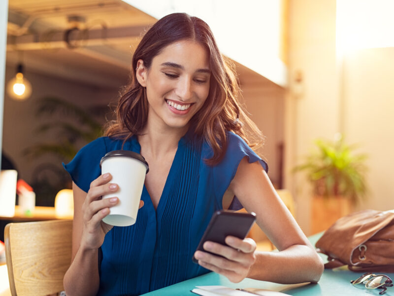 Young,Beautiful,Woman,Holding,Coffee,Paper,Cup,And,Looking,At