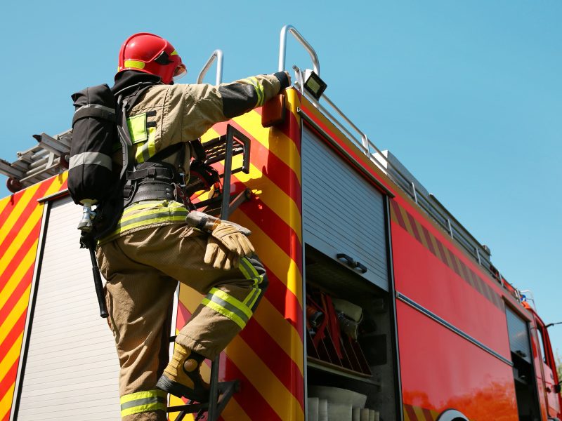 Firefighter,In,Uniform,On,Fire,Truck,Outdoors,,Back,View